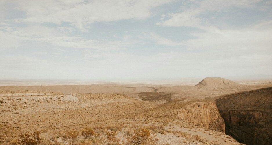 Weite, karge Wüstenlandschaft mit Felsklamm und trockenem Hochplateau