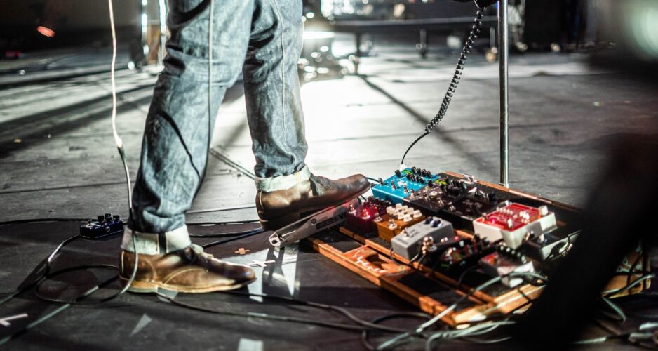 Gitarrist mit Schuhen über einem Pedalboard auf einer Konzertbühne