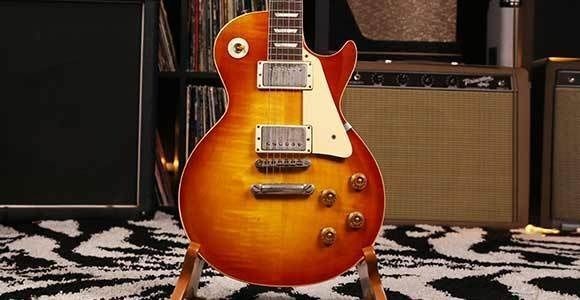 Orangefarbene E-Gitarre vor mehreren Röhrenverstärkern auf einem Teppich